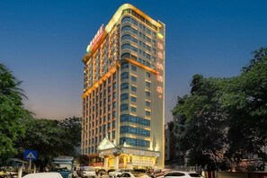 A tall hotel with multiple floors, a prominent entrance, and a sign indicating it is a Vienna Hotel. - Vienna Hotel (Shenzhen)