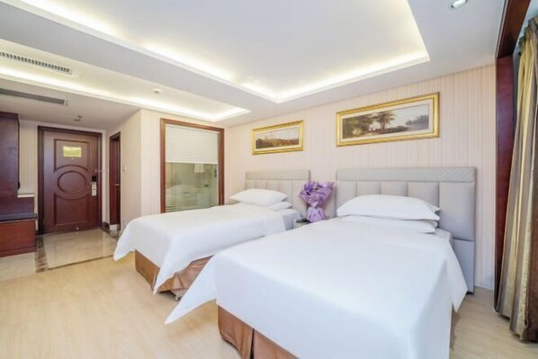 Two single beds with white linens and a wooden headboard.