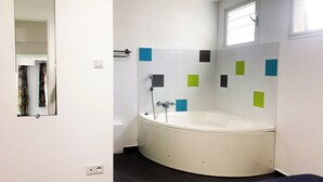 A bathroom with a bathtub, a mirror, a window, and a tiled wall. - Two-bedroom apartment Grand fond Saint-Leu vacation residence (Saint-Leu)