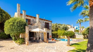 A stone building with a patio, outdoor seating, and a swimming pool.