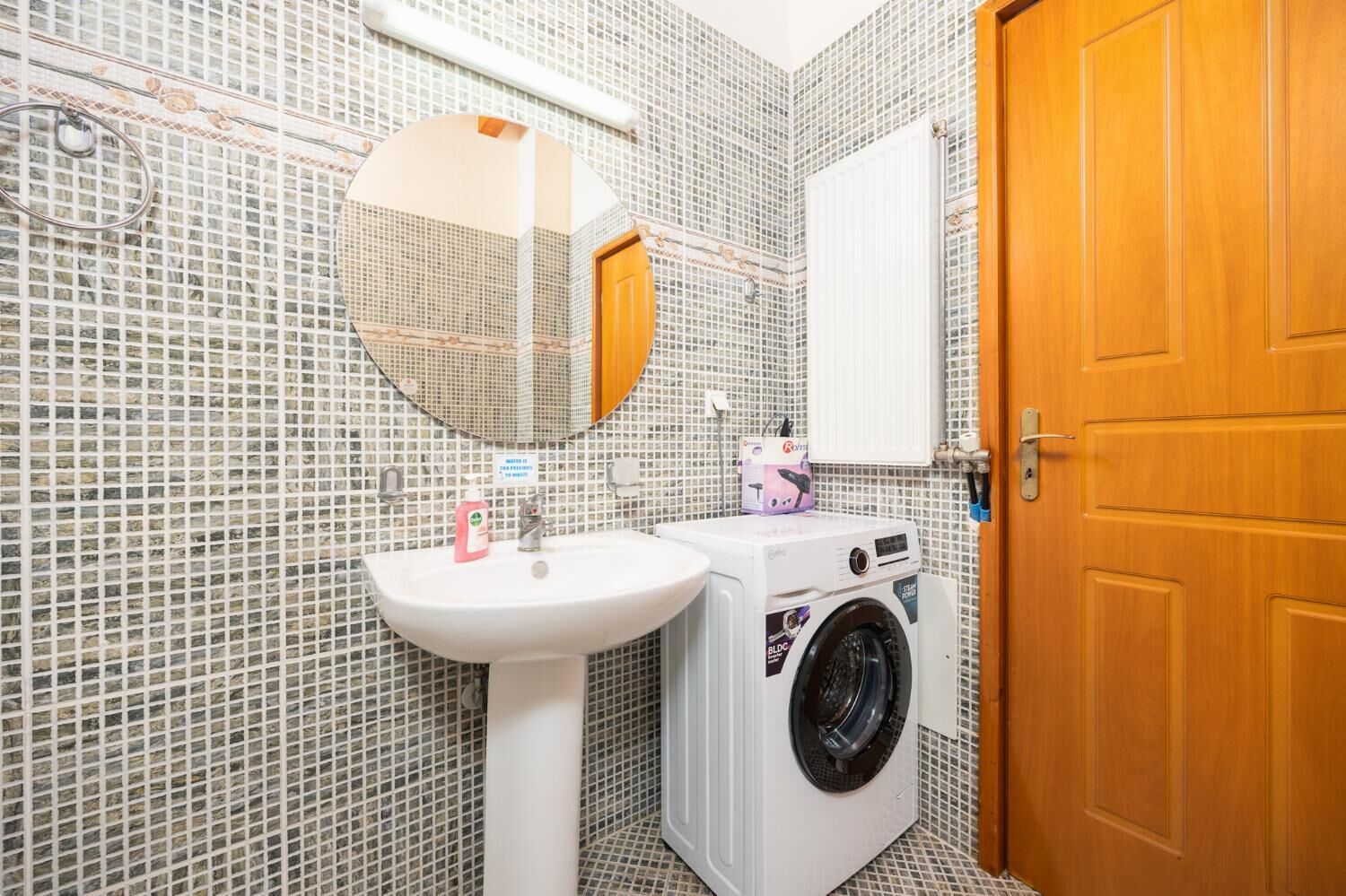 Un baño con lavamanos, espejo y lavadora.
