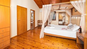 A spacious bedroom with a wooden floor, a large bed with white linens, a wooden wardrobe, and a wooden ceiling. - Villa Top Hill - Three Bedroom Villa, Sleeps 6 (Agia Triada)