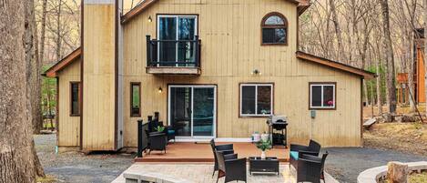 A two-story house with a patio area featuring outdoor furniture and a fire pit.