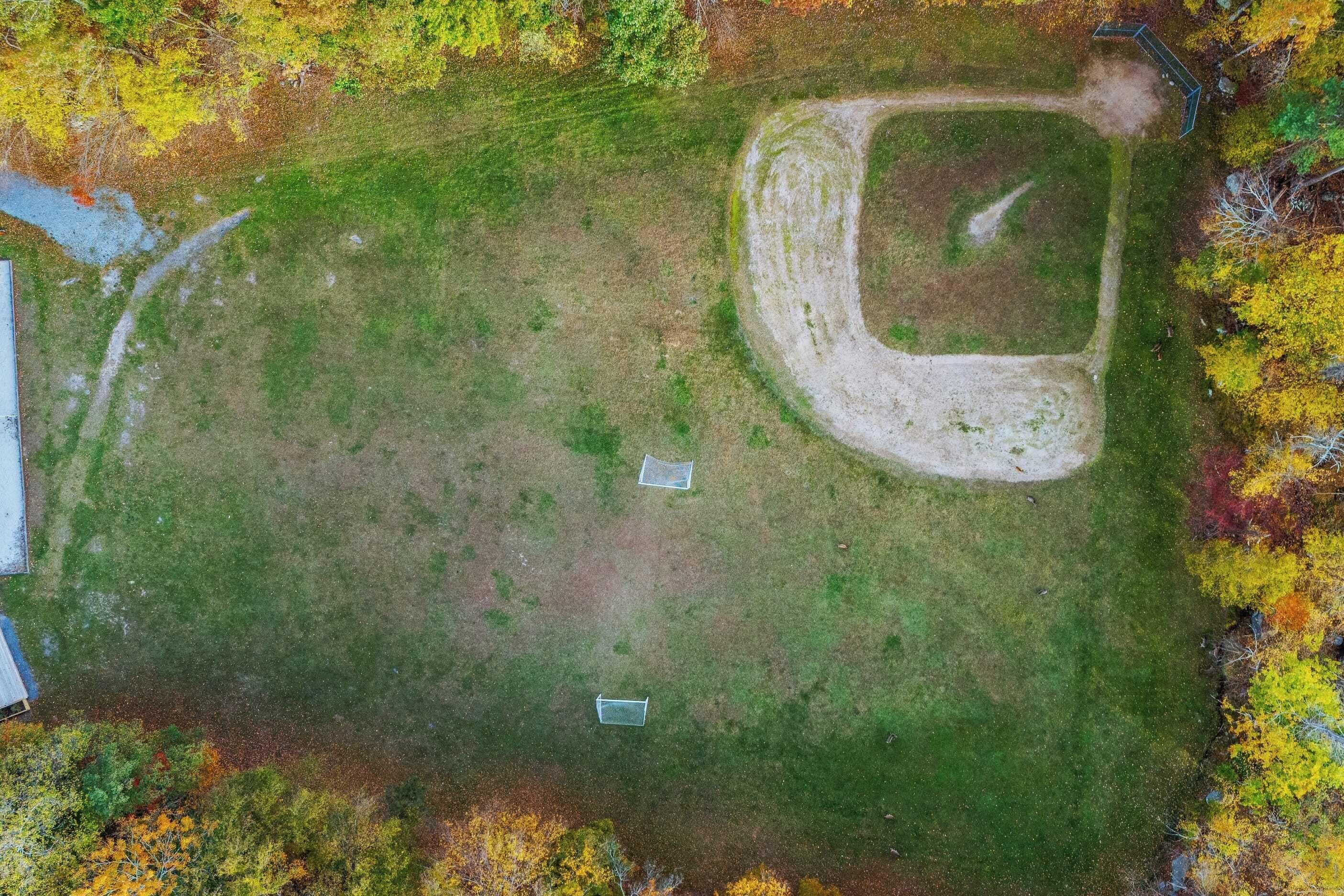 Luchtbeeld van een grasveld met een onverharde pad en twee rechthoekige objecten.