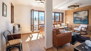 A modern living room with a sofa, chairs, a coffee table, and a painting on the wall. - Écrin – Stylish alpine escape in Alpe d'Huez (Alpe d`Huez)