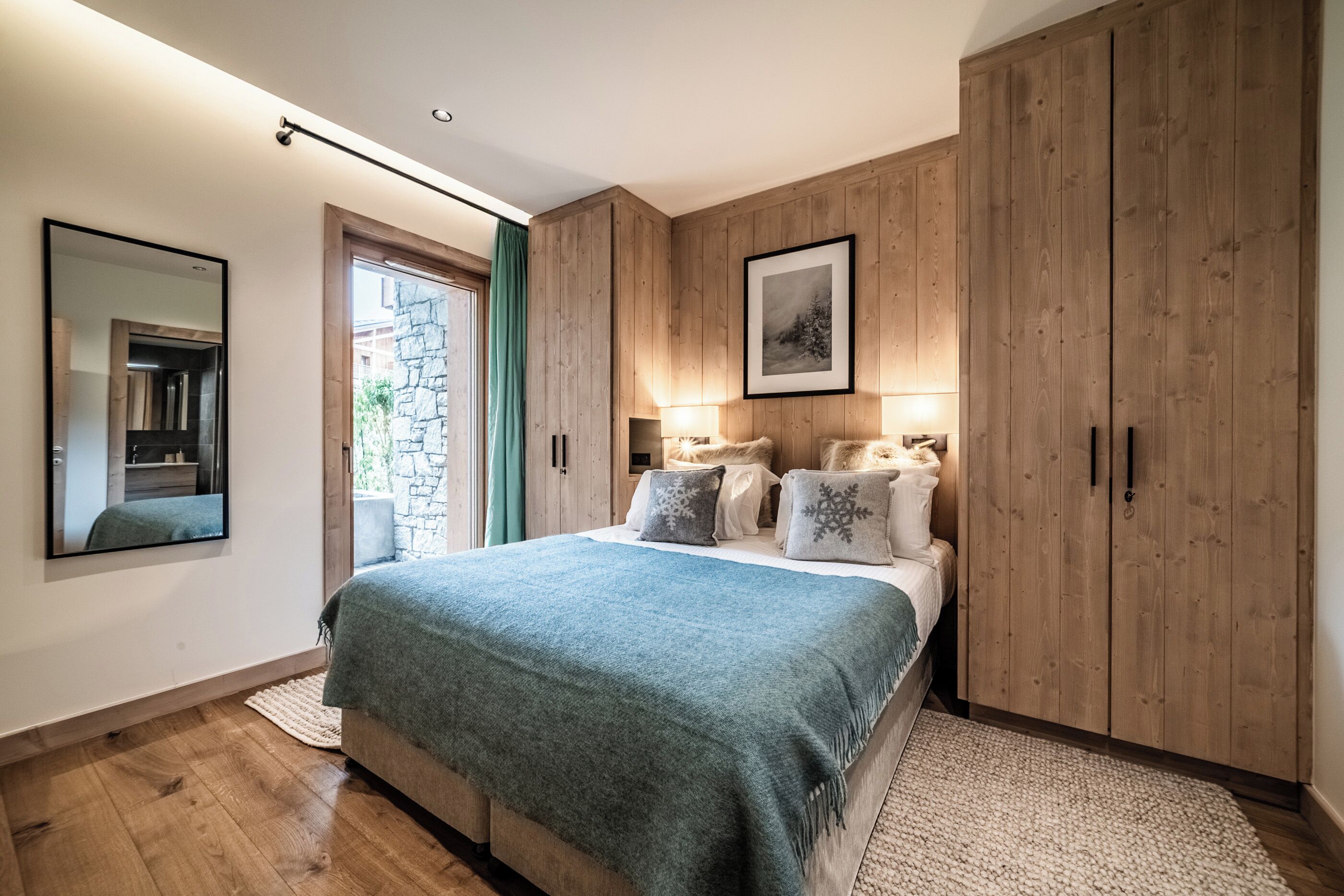 Un dormitorio con una cama grande, un armario de madera, un espejo y un cuadro en la pared.