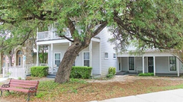 A two-story house with a porch and a large tree in front. - The Salado Inn Kolb Suite (Salado)