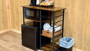 Eine kleine Küchenzeile mit einer Mikrowelle, einem Kühlschrank und einer Kaffeemaschine auf einem Holzboden.