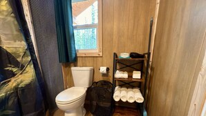 Ein kleines Badezimmer mit Toilette, Ablage für Handtücher und einem Fenster.