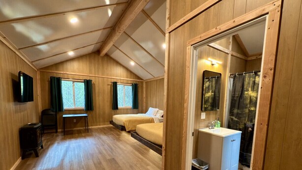 Ein Holzinterieur mit zwei Betten, einem Schreibtisch und einem Badezimmer.