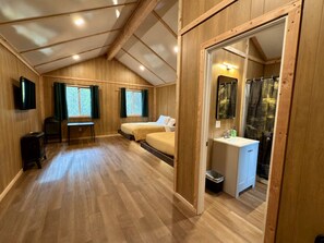 A wooden interior with two beds, a desk, and a bathroom. - Roberts Lodge in Tok, Alaska (Tok)