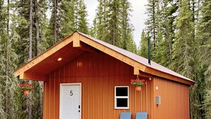 Eine kleine Holzhütte mit einer weißen Tür, zwei Stühlen davor und der Nummer 5 an der Tür.