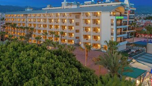 A multi-story hotel with a rooftop pool area, surrounded by lush greenery. - Sun Heaven Queen (Alanya)