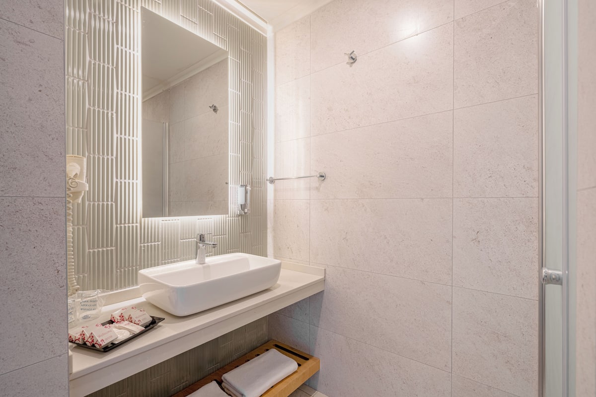 A modern bathroom with a large rectangular sink, a mirror, and a shower area.