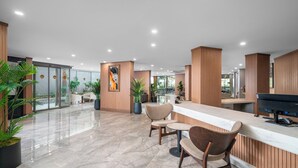 A modern lobby with a reception desk, seating area, and large windows. - Sun Heaven Queen (Alanya)