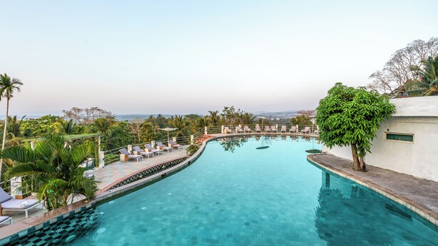 A swimming pool with lounge chairs and palm trees.