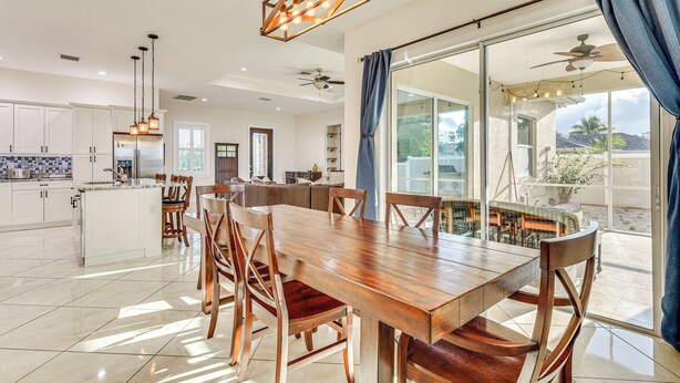 A spacious kitchen with white cabinets, a large island, and a dining area with a wooden table and chairs.