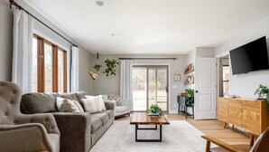 En stue med sofa, lænestol, sofabord og fjernsyn.