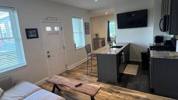 Een moderne woonkamer met een grote bank, een eethoek met een tafel en een keuken met een geïntegreerd barretje.