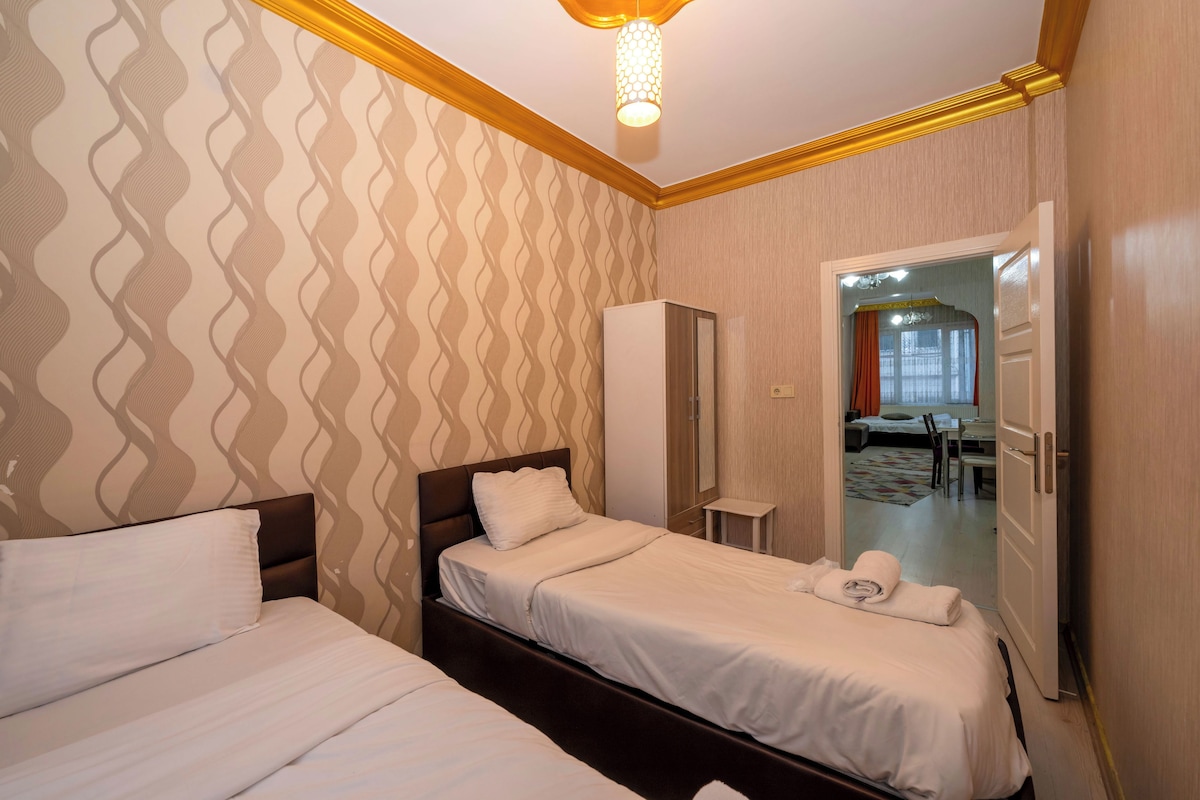 Een hotelkamer met twee bedden, een garderobe, een spiegel en een deur naar een eetgedeelte.