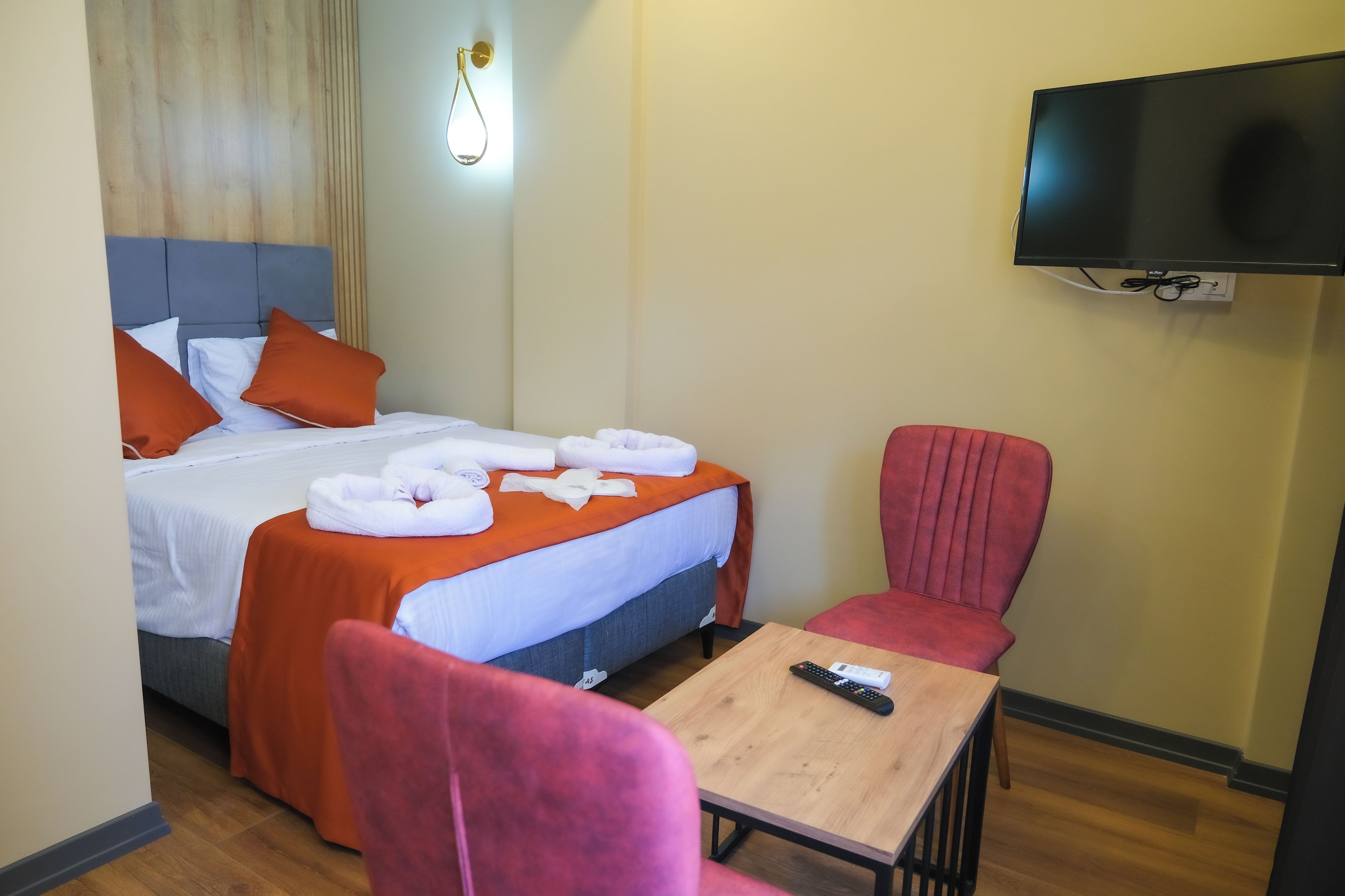 A hotel room with a bed, a TV mounted on the wall, a table, and a chair.