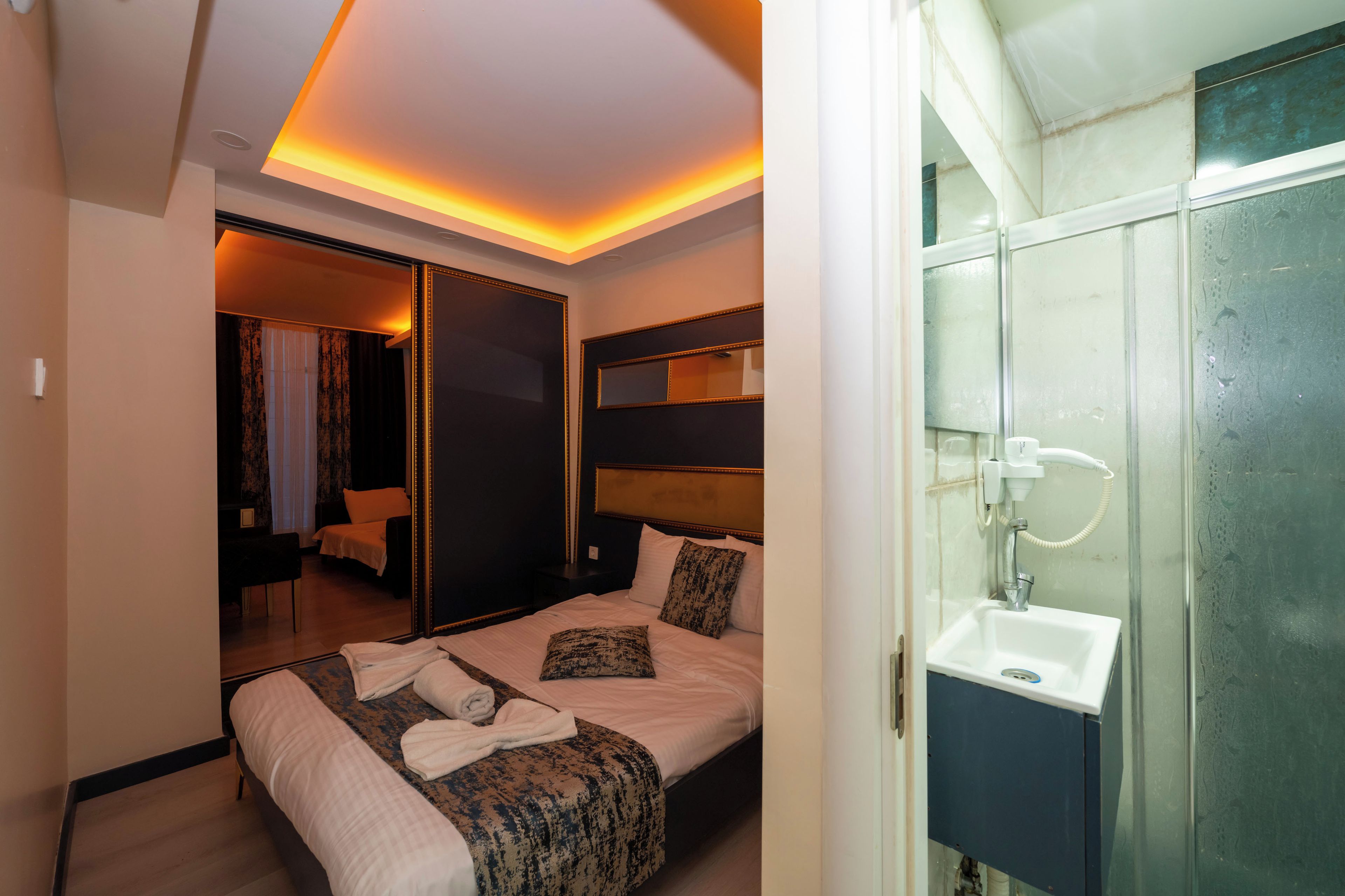 Ein Hotelzimmer mit Bett, Nachttisch, Spiegel und einem Badezimmer mit Waschbecken und Dusche.