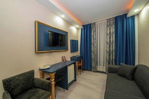 A modern living room with a TV, a small desk, and two sofas. - La Vitinre (Istanbul)