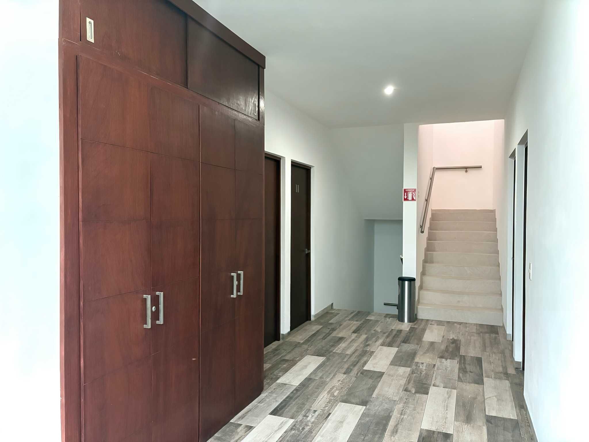 Ein Flur mit einem Holzschrank, einer Treppe und einem Mülleimer.