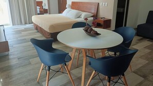 A hotel room with a bed, bedside table, lamp, and a round table with chairs. - Tropical Elegance Studio CondoHotel  (Puerto Morelos)