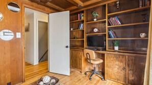 Ein Zimmer mit Holzwänden, einem Schreibtisch, einem Stuhl und Bücherregalen.