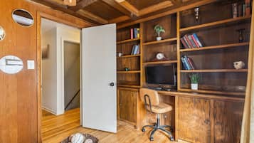 Un interior de madera con un escritorio, una silla, estanterías y un televisor.