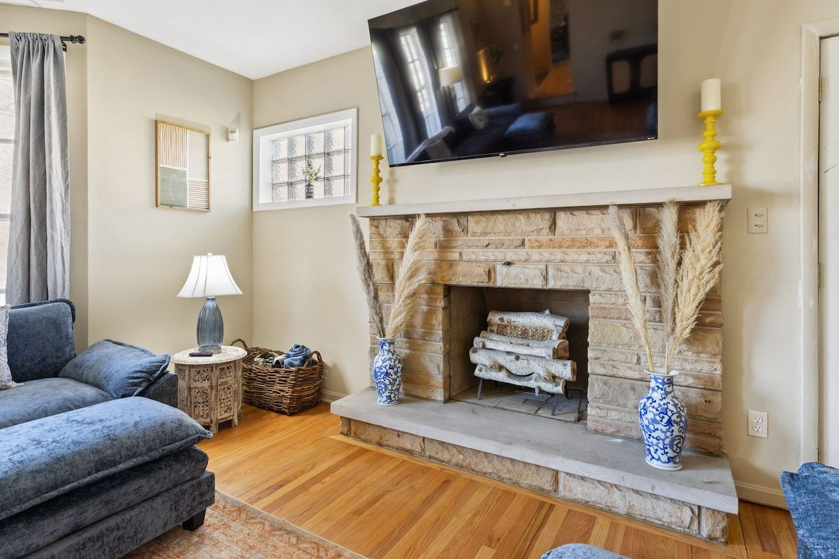 Una sala de estar con chimenea, un sofá, un televisor y un florero.