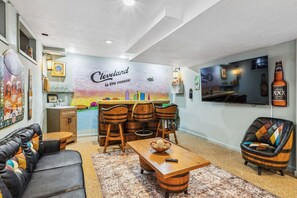 Un salon comprenant un coin bar, un canapé, une table basse et un téléviseur fixé au mur.