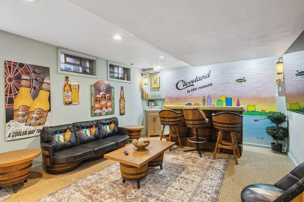 Un salon chaleureux avec un canapé, une table basse et des tabourets de bar. Un mur est décoré d’une fresque représentant un paysage urbain, et on y trouve également l’inscription : « Cleveland, c’est ce qui compte. »
