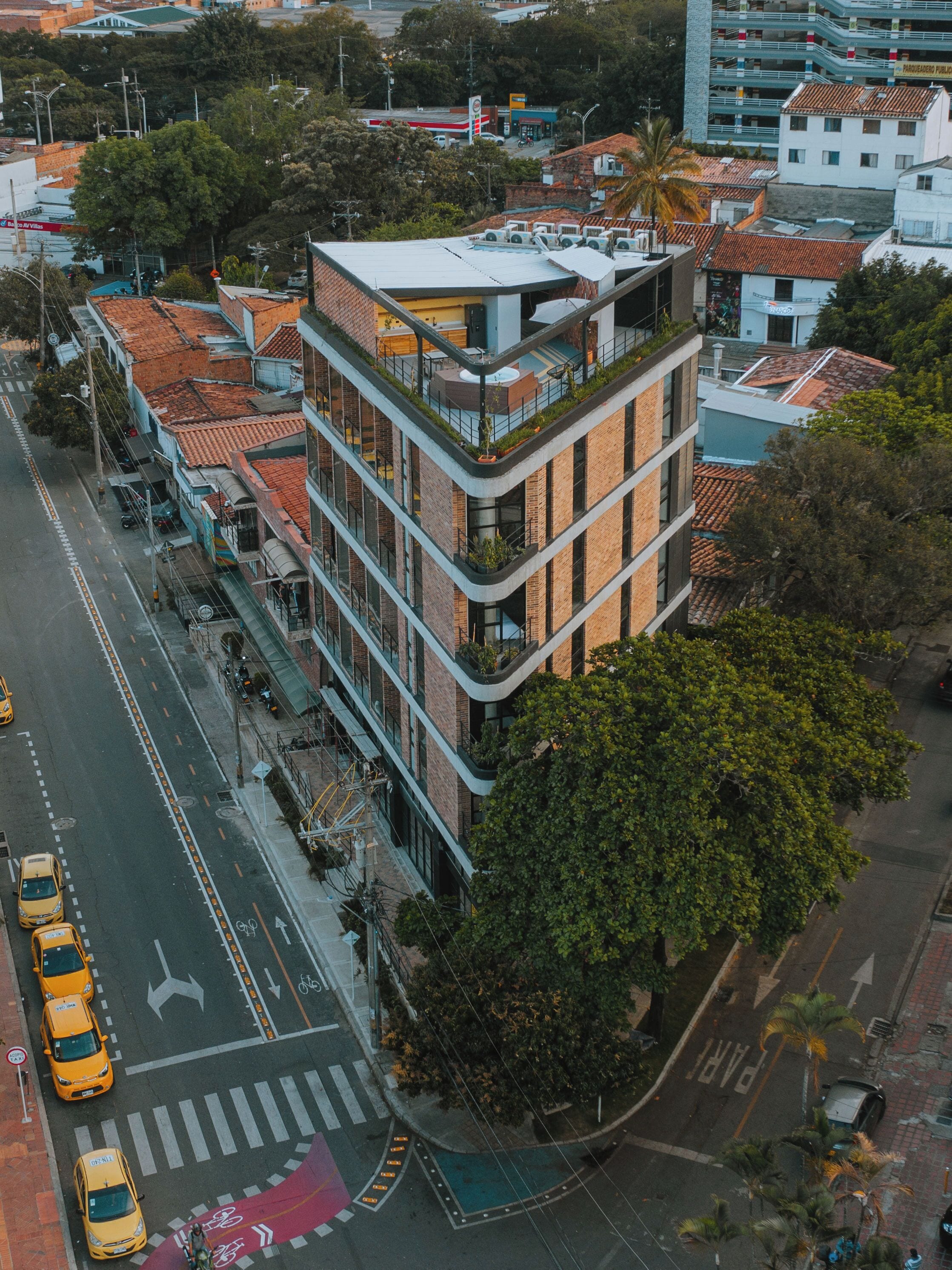 Un edificio a più piani con un giardino pensile, circondato da strade cittadine e altri edifici.