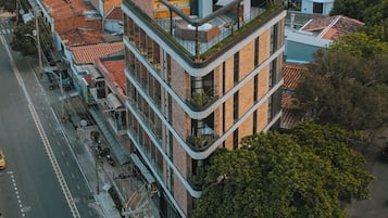 Un edificio a più piani con un giardino pensile, circondato da strade cittadine e altri edifici.