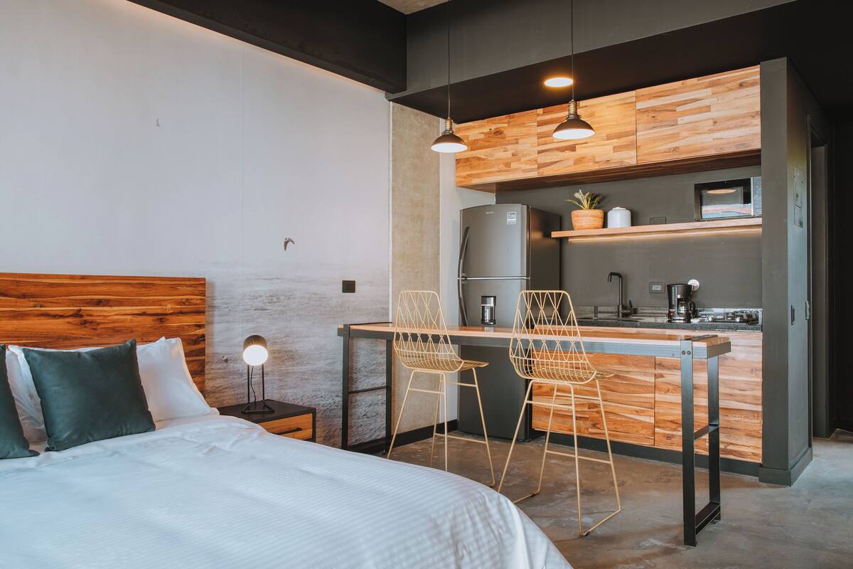 A modern bedroom with a large bed, a small desk, and two chairs.