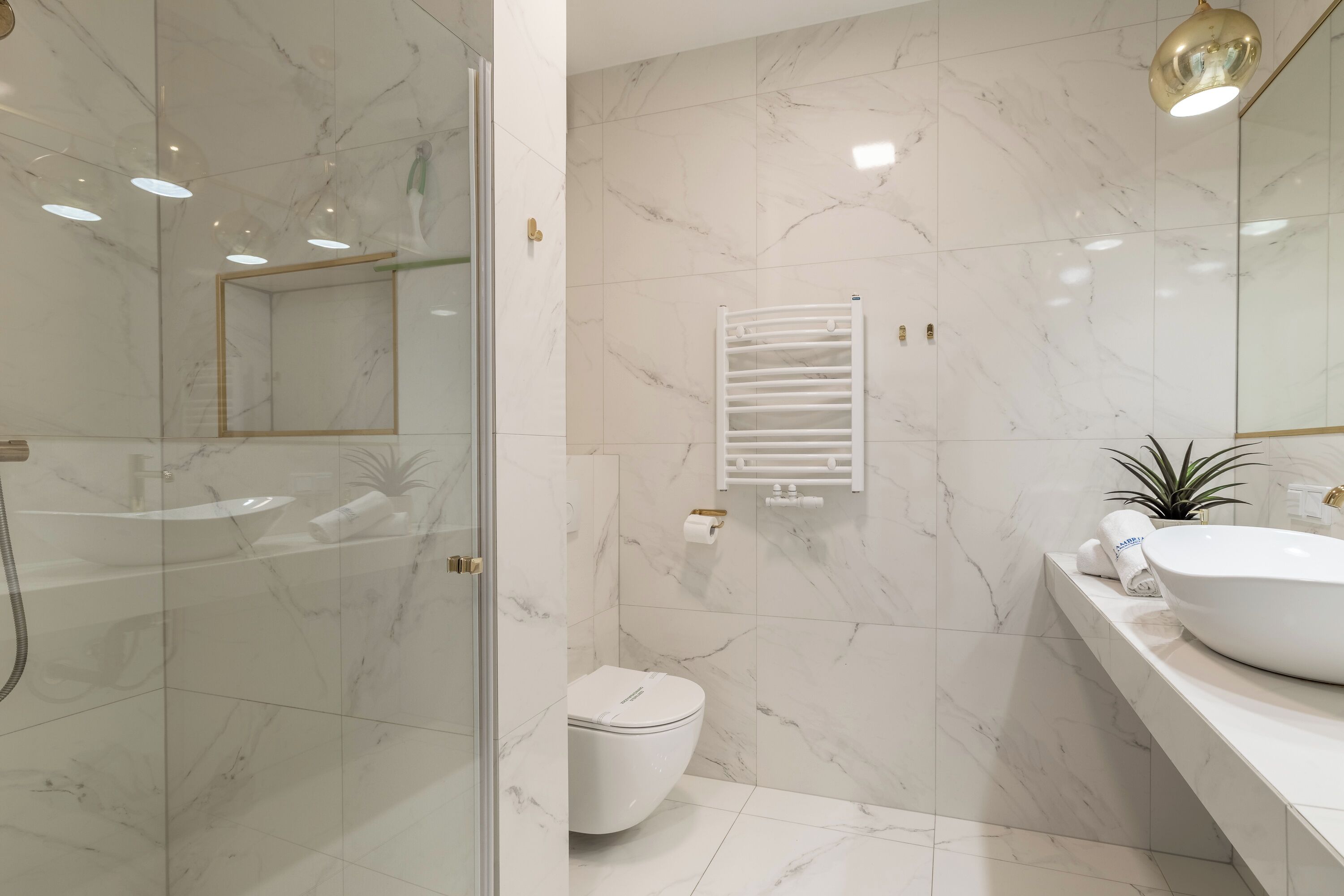 Ein modernes Badezimmer mit Duschkabine aus Glas, einer weißen Toilette und einem großen, weißen Waschbecken mit Schüssel.