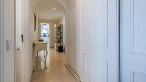A hallway with a white door, a small table with a bowl, and a black bucket on the floor.