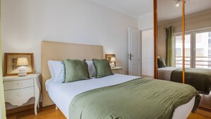 A hotel room with a bed, nightstands, a mirror, and a window with curtains.