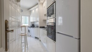 A modern kitchen with white cabinetry, a built-in washing machine, a double oven, and a clock on the wall.