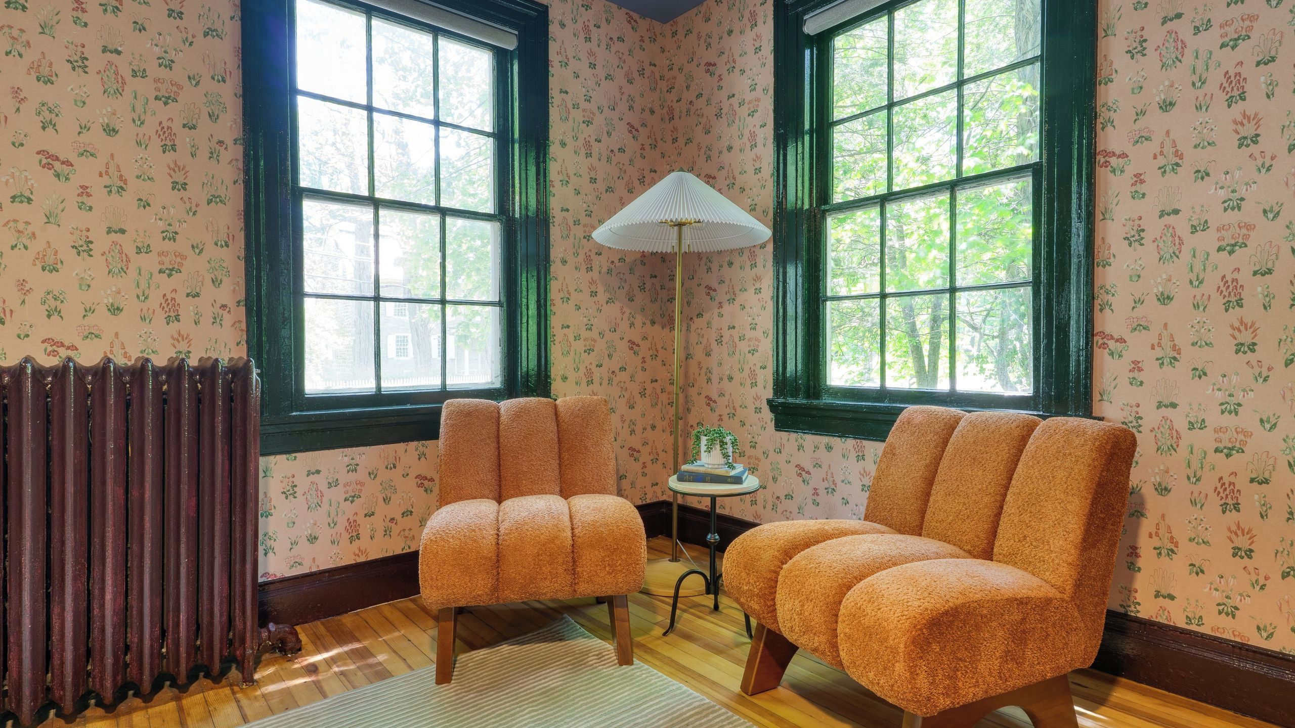A room with two upholstered chairs, a floor lamp, and a radiator.