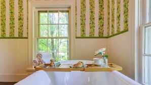 Ein Badezimmer mit einer Badewanne, einem Fenster und einem Holztablett mit Handtüchern und Pflegeprodukten.