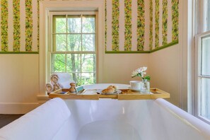 Un baño con bañera, ventana y una bandeja de madera con toallas y artículos de aseo.