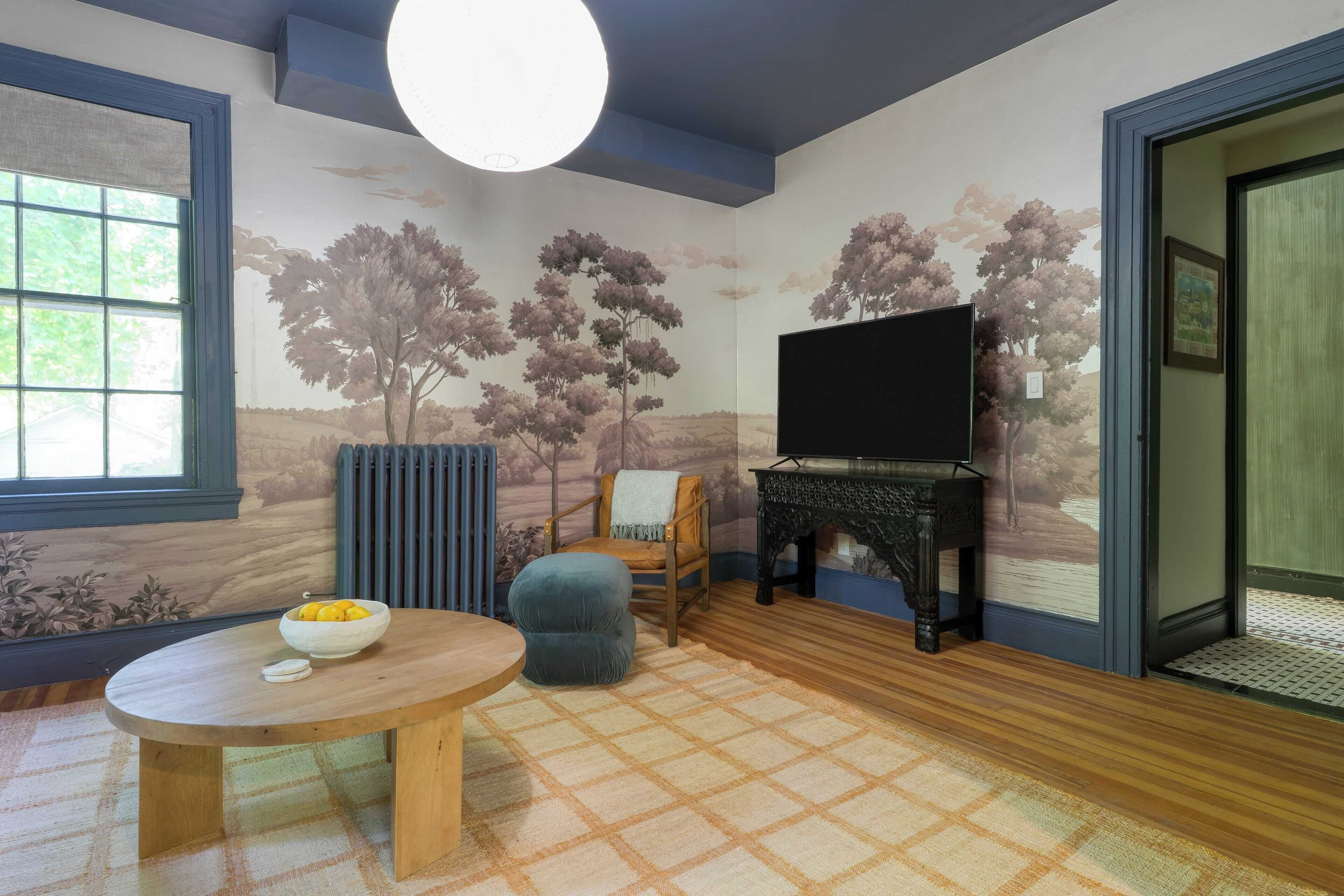 A room with a wooden table, a blue chair, a television, and a fireplace.
