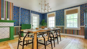 A dining area with a wooden table and chairs, a radiator, and a plant. - Relax in Style at Historic Modern on Main With Modern Amenities & Wooded Views (Stone Ridge)