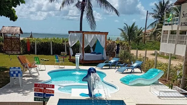 Una piscina con una fuente en forma de delfín, sillas de descanso y juguetes inflables.