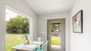 A dining area with a table and chairs, a door leading outside, and a framed picture on the wall.