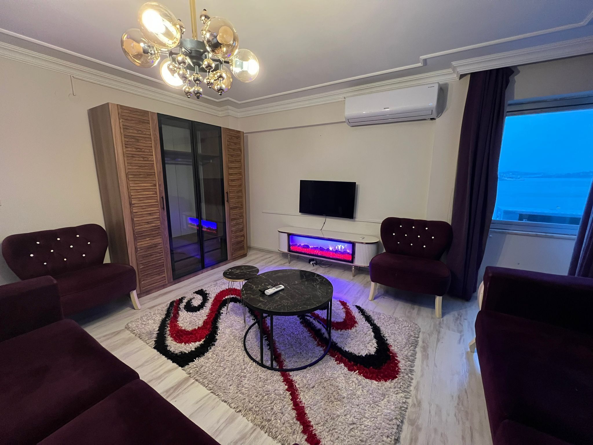 Un salon moderne avec un téléviseur, un meuble de rangement pour les appareils multimédias et un espace détente.