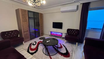 Un salon moderne avec un téléviseur, un meuble de rangement pour les appareils multimédias et un espace détente.